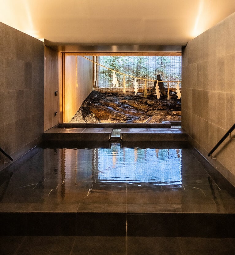 「恩湯」の浴槽は、奥の岩盤から湧出する温泉を受け止めるように作られている。