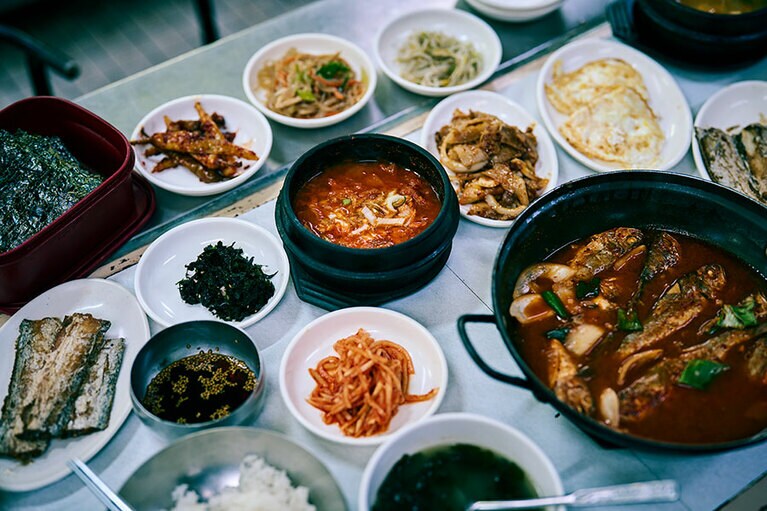 名物メニュー定食（チョンシッ）W8,000。太刀魚や鯖など季節によって変わる焼き魚、ナムル、キムチなどのパンチャン（おかず）、目玉焼き、炙った海苔とご飯。そして旅の朝ごはんに嬉しいテンジャンチゲ、ミヨックッ（わかめスープ）、キムチチゲと3種のスープがついてくる。