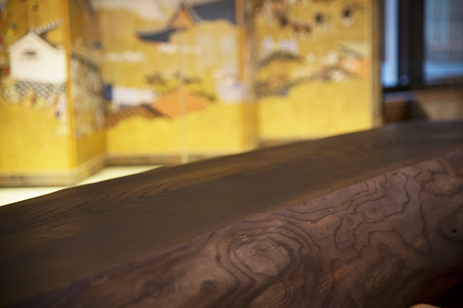 葛飾北斎の浮世絵を描いた金屏風を臨む、神代欅(じんだいけやき)の一枚板のカウンターでチェックイン。