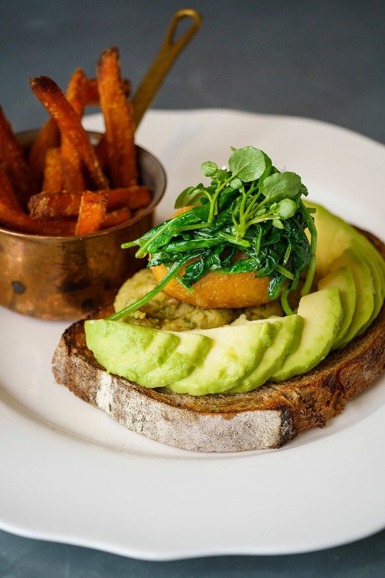 ボリュームたっぷりで嬉しい“ポーチドエッグ、フムス、アボカド、ほうれん草をのせた全粒粉トーストとフライドスウィートポテト” 18ユーロ。