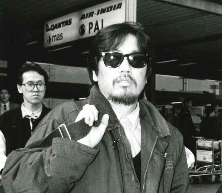 1988年、テレビ朝日のドキュメンタリー「疾風のアラビア～天地創造の大地を走る」撮影のために訪れた中東から帰国したジュリー。ところで、背後にいるのは、若き日の芸能レポーター・井上公造氏ではなかろうか。