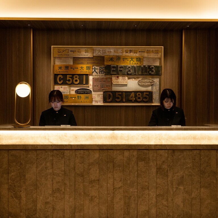 11:51 ベルデスクでスタッフがお出迎え。壁に機関車のプレートや行先表示板を使ったアートが飾られ、旅心をそそります。