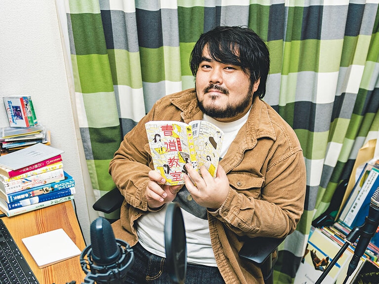 マンガを読む定位置は数々の名曲が生まれた作業台。「この場所が、本棚が見渡せていいんです。目に付いた作品から曲のヒントを貰うことも」。本棚にCDやDVDが混じっているのもミュージシャンらしい。