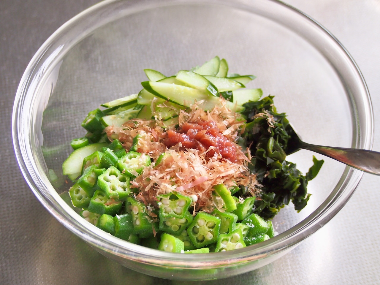 茹でたオクラは水で洗いながら冷ます。ヘタを切り落とし、5mm幅に切り、（1）の食材、鰹節と共にボウルに入れ全体を混ぜる。