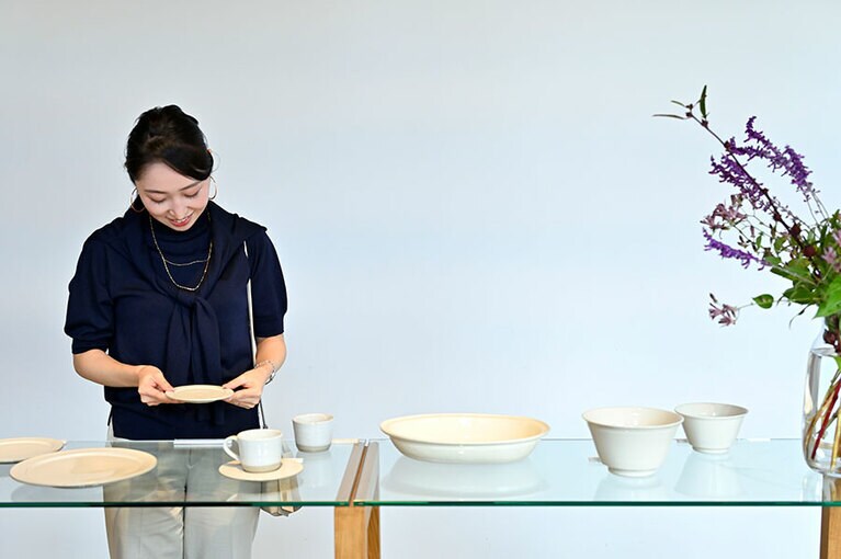 ショップコーナーで器を手にする磯村さん。「地元の石見焼や、石州 (せきしゅう)瓦とコラボしたお皿など、とても素敵ですね」。