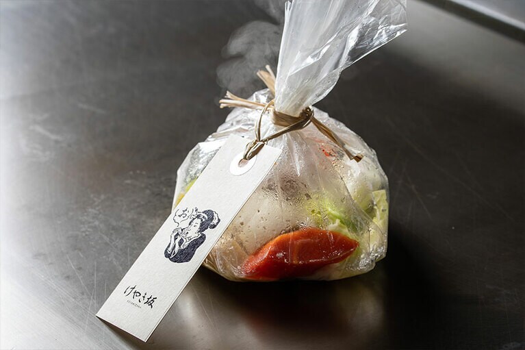 魚の包みを開くと一気に香りが広がる。香り高いトリュフ・オニオンソースと合わせると絶品。