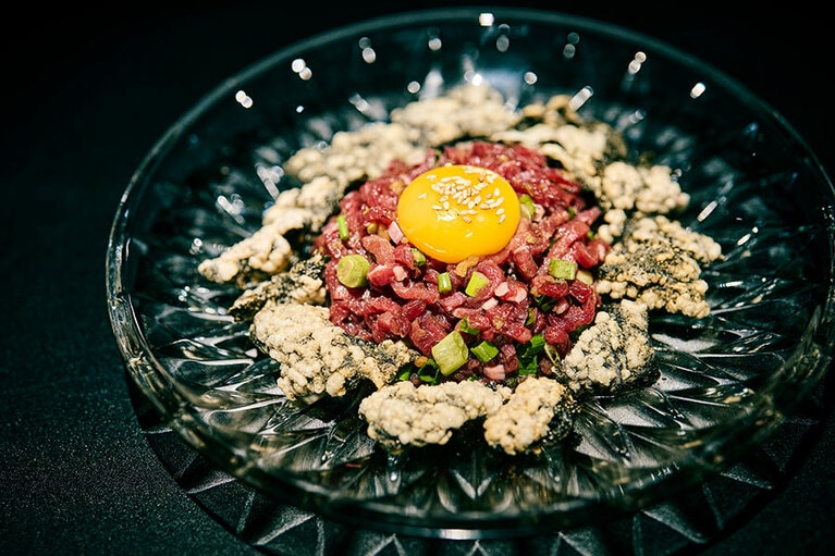 ユッケ W20,000。皿にぐるりと添えられたプガク（海苔のスナック）と卵黄を混ぜると肉の甘みとプガクの塩気が絶妙にマッチ。