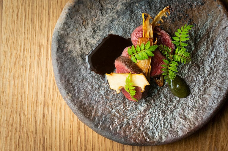 メインディッシュのひとつ「鹿肉 筍 木の芽味噌」。春先に獲れた鹿肉は、さっぱりしているのが特徴。山椒の木の芽を「甲州味噌」と合わせてペースト状にしたソースと、白樺の樹液を500倍に薄めてワインと一緒に煮詰めたソースを順に絡めていただく。※メニューは季節や日によって変わります。