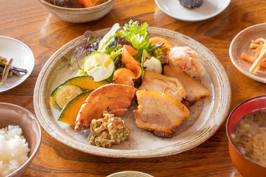 「うぶすなの家」のお母さんが作る季節の小鉢と妻有ポークの煮豚＆車麩の山菜だれ 2,000円(税込)。photo Sakamoto Isamu