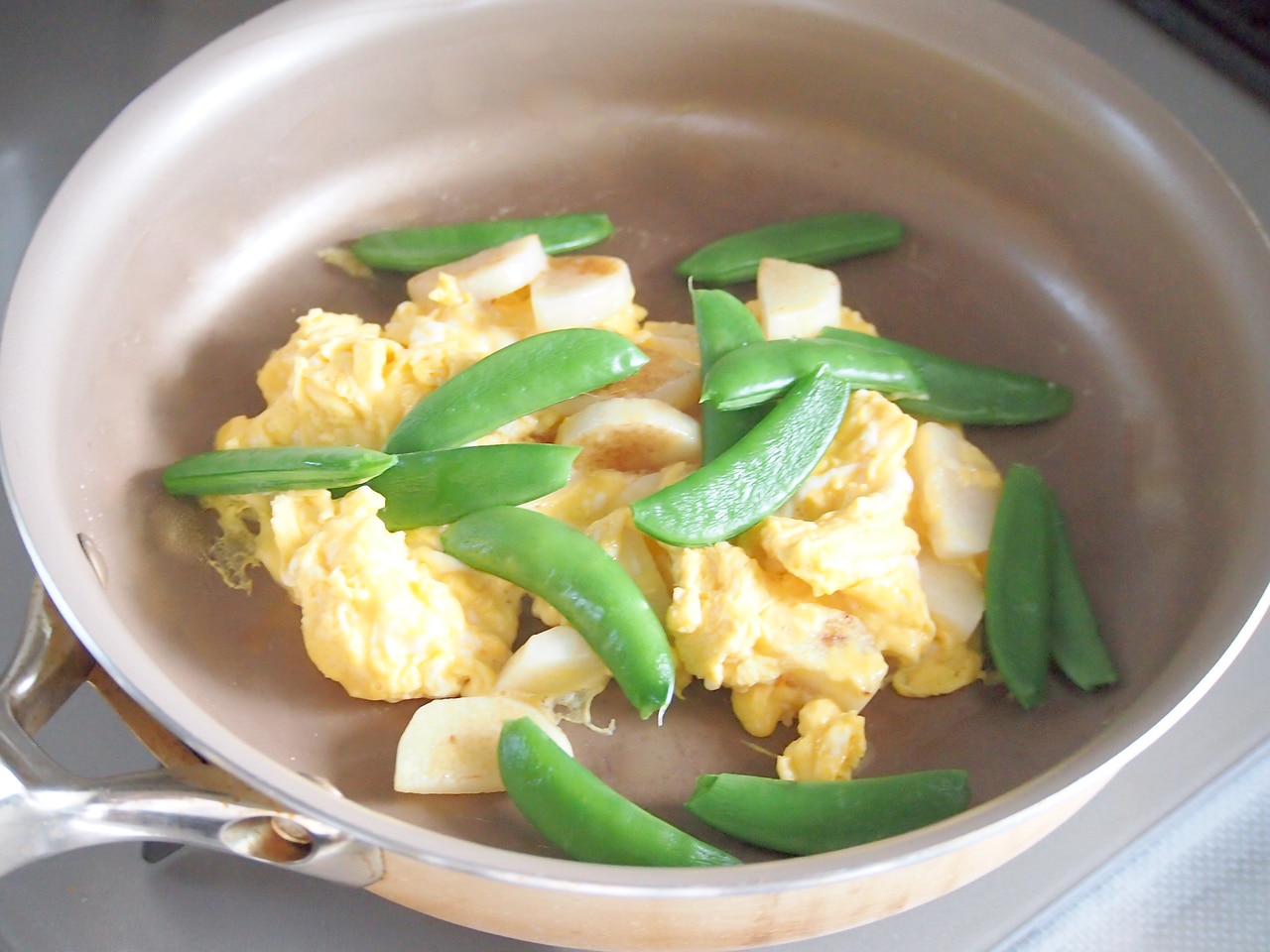 卵が半熟状に固まってきたら、スナップエンドウを入れる。