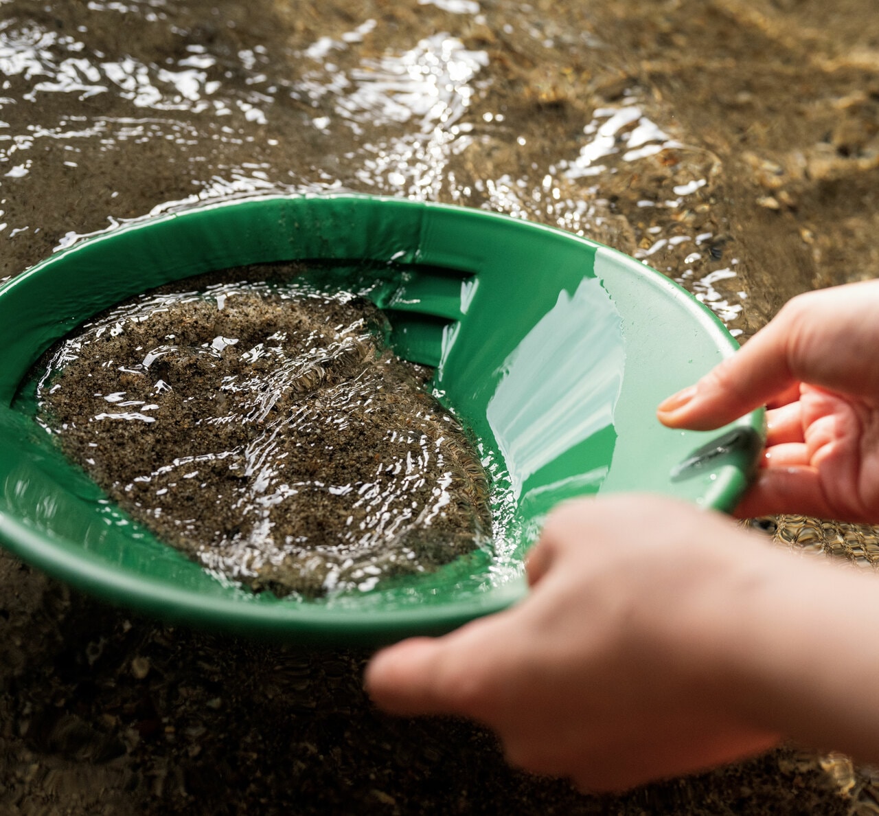 水中で砂利をゆすって砂金を沈澱させたら、上部の砂を取り除いていきます。