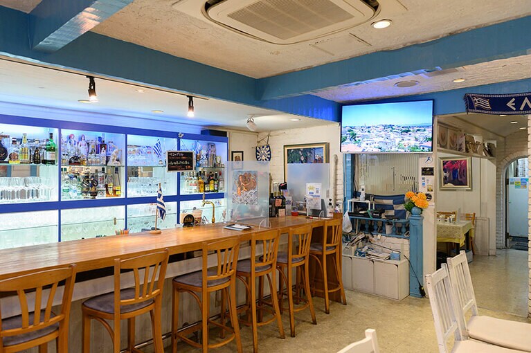 太陽の光を受けた白い家や青い空とエーゲ海の世界を感じる、明るく開放感のある店内。