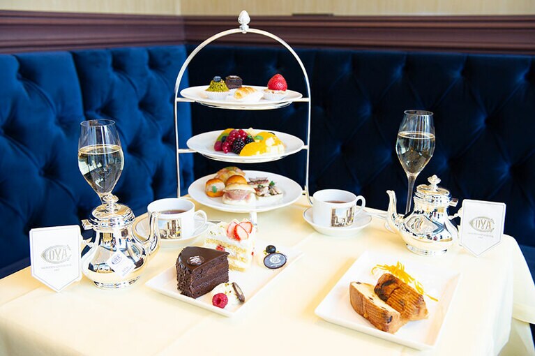 アフタヌーンティー DELUXE。紅茶またはハーブティのティーポット、本日のケーキ、カナッペ、フルーツの盛り合わせ、ミニサンドイッチ、ミニペストリー、プラリネがいただける。2名様分で9,000円(税込)。シャンパーニュ付きの場合は、2名様分で12,000円(税込)。