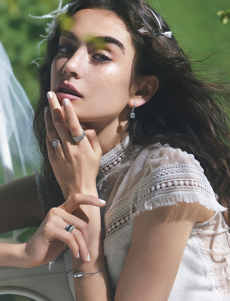 「ヴァンドーム リズレ」ソリテール リング〈左手薬指〉(WG×DIA×センターDIA0.5ct×ブラックラッカー) 1,320,000円、イヤリング(WG×DIA×ブラックラッカー) 1,544,400円、「キャトル ラディアント」ダイヤモンド リング スモール〈左手人差し指〉(WG×DIA) 968,000円、「キャトル ブラック」ダイヤモンド リング ラージ〈右手薬指〉(WG×DIA×ブラックPVD) 1,267,200円、「ジャック ドゥ ブシュロン」ブレスレット(WG×DIA) 1,346,400円、「フレシュ」髪飾りにしたシングル スタッズイヤリング(WG×DIA) 1,927,200円／すべてブシュロン(ブシュロン クライアントサービス)、ドレス 374,000円(レンタル価格)／レンボ・スタイリング(ドレスモア)、フェザーのヘッドドレス 7,700円(レンタル価格)／リチャード・デザインズ(ミラー ミラー 丸の内)、椅子にかけたベール／エディター私物