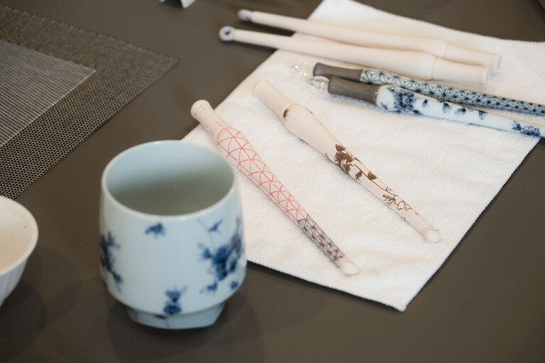 茶色の絵付けは、焼くとブルーに。均一な太さで描きあげる筆使いに熟練の技が炸裂。