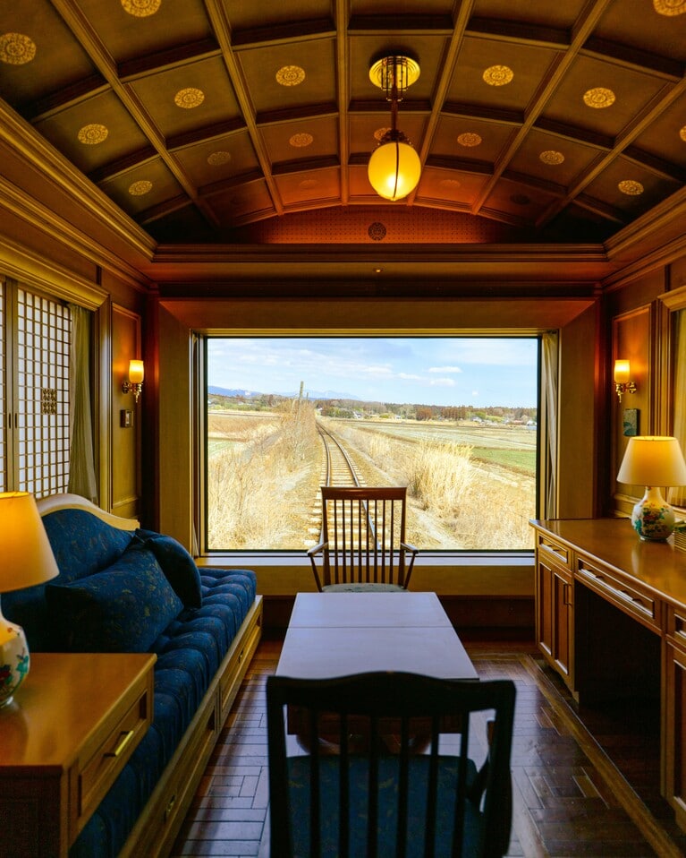 「ななつ星 in 九州」の贅沢な旅を象徴する客室「DXスイートA」。額縁のような窓から過ぎ去る風景を眺めていると、心がふっと軽くなり、まるで “動く瞑想” とでもいうようなマインドフルな時間が訪れます。