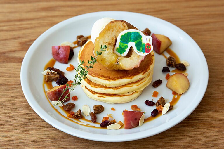 シナモンがほのかに香る大人にも嬉しい、焼きりんごのパンケーキ 1,600円。グリルしたりんごは、絵本の中にある穴あきのしかけをイメージしている。イチジクやレーズンなどのドライフルーツが散りばめられ、秋らしく仕上げられている。