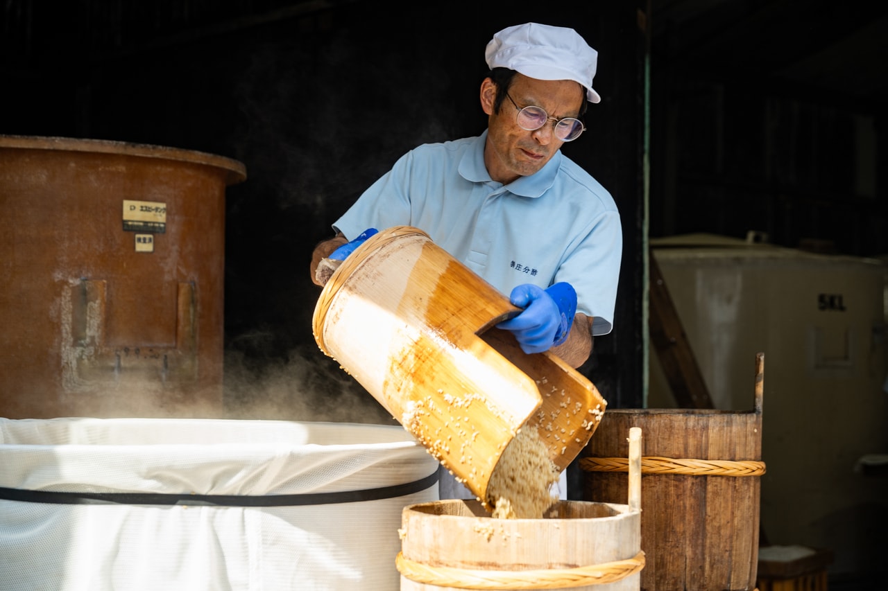 玄米の質感を確かめながら、手作業で窯から桶に移し替える。