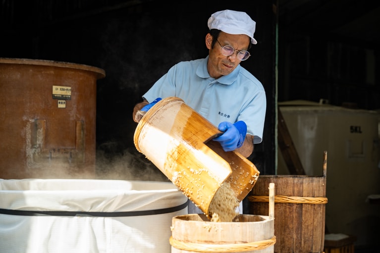 玄米の質感を確かめながら、手作業で窯から桶に移し替える。