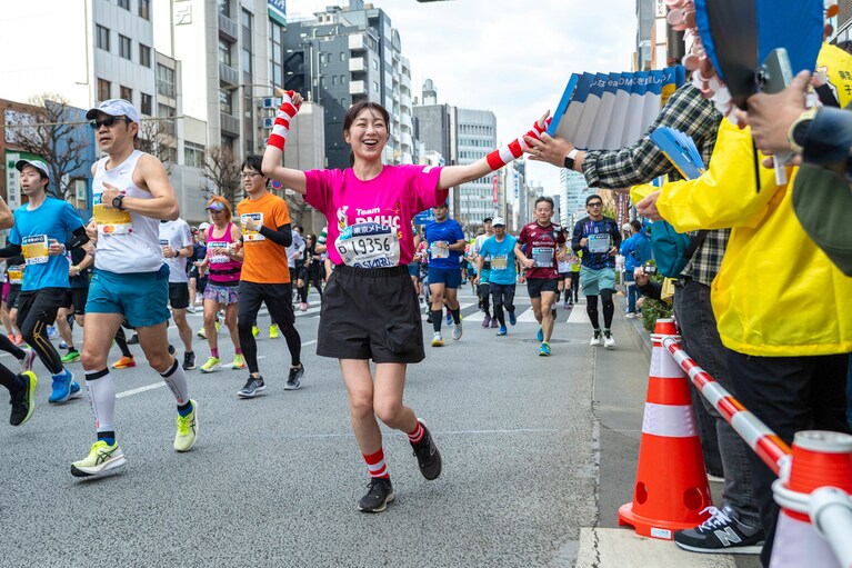 沿道のTeam DMHC応援団の前を駆け抜ける高田夏帆さん。　©東京マラソン財団