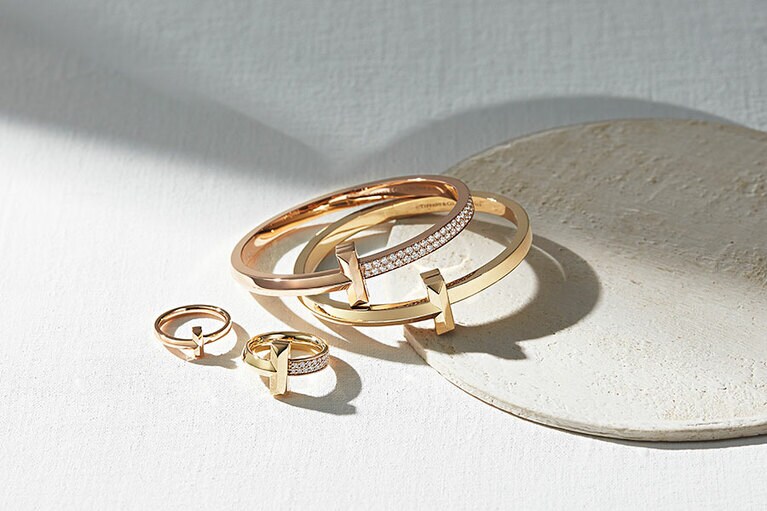 上から時計回りに：ティファニー Tワン ワイド ダイヤモンド ヒンジ バングル(ローズゴールド×ダイヤモンド)2,970,000円、ティファニー Tワン ワイド ヒンジ バングル(イエローゴールド)880,000円、ティファニーTワン ワイド ダイヤモンド リング(イエローゴールド×ダイヤモンド)539,000円、ティファニーTワン ナロー リング(ローズゴールド)148,500円／ティファニー(ティファニー・アンド・カンパニー・ジャパン・インク)
