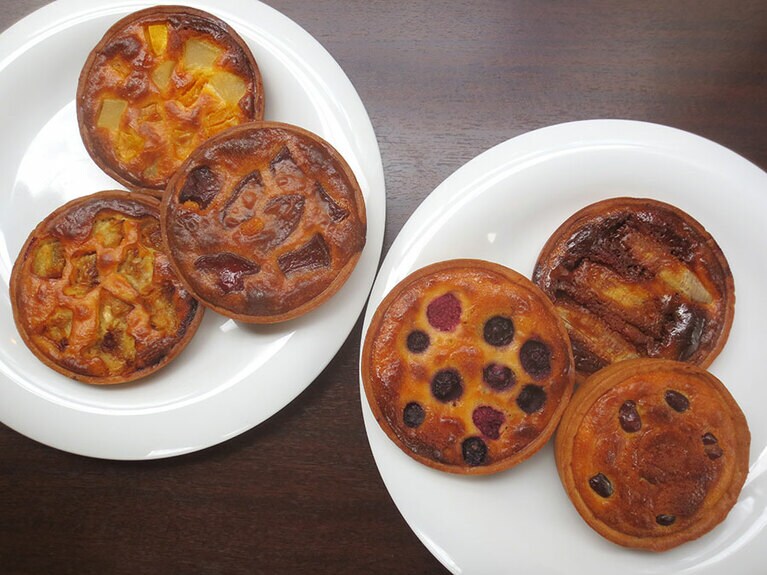焼きタルト6種。左の皿、上より時計回りに「マンゴーと洋梨」、日替わりの気まぐれおやつ「りんご」、季節限定の「いちじく」。右の皿、上より時計回りに「キャラメルバナナ」「あんことおもち」「ブルーベリー」。各200円。
