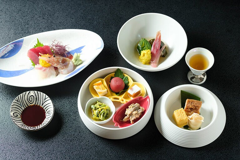 球型三段重の一段目は、ばってら寿司と厚焼き玉子のおしのぎ。二段目は山菜のみずこぶや、あけび味噌、あんぽ柿など山らしい前菜が。三段目はヒラメを昆布で巻いた龍飛巻きの酢の物。写真左上はお造り。