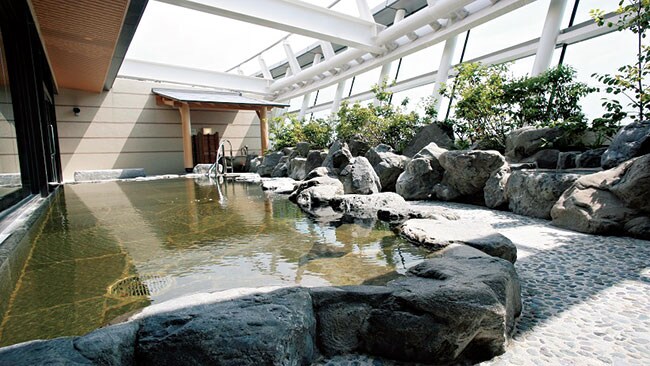 街中にあるビジネスホテルの天然温泉の多くは、地下を深く掘って汲み上げた自家源泉。岩や木などを配した自然を感じさせる演出も、温泉宿チックな気分を味わえるポイント。写真は「シティプラザ大阪HOTEL＆SPA」の露天風呂。「天然温泉」は当たり前!?