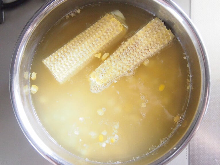 (2) 鍋に水、トウモロコシの実と軸を入れて加熱します。トウモロコシの軸には甘みがたっぷり含まれているので、ぜひ捨てずに使いましょう。