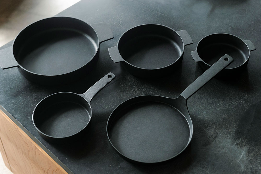 独特の質感の黒は“釜定ブラック”と呼ばれる。下地の熱処理や手間が違う。シャロウパン 9,350円、組鍋 3,300円～。