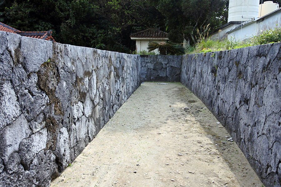 高良家住宅へ続くサンゴの石塀。建物は台風対策のため、周囲の地盤よりも低い位置にあります。