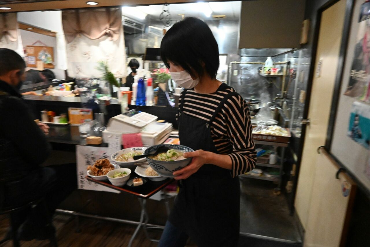 客が多い。急ぎ足でラーメンを運ぶ（満洲味）