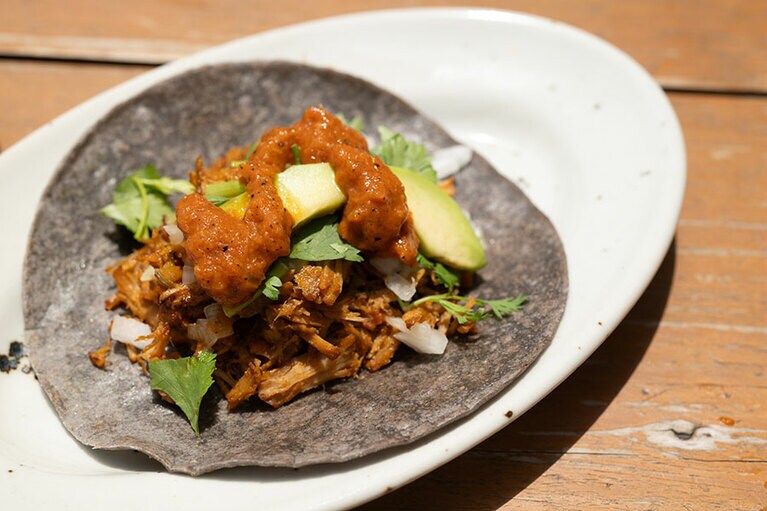 火曜日のお楽しみ「タコス」。ブルーコーンを使った皮の上には豚肉、アボカド、香菜、玉ねぎがたっぷり（500円）。