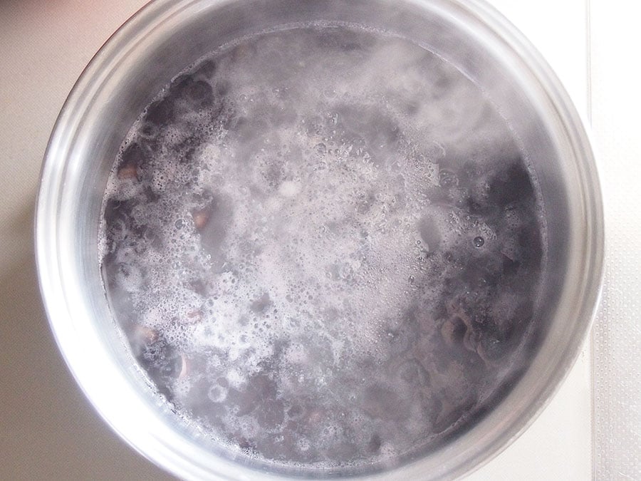 (2) 黒豆を、戻し汁ごと鍋に入れて弱火で煮ます。