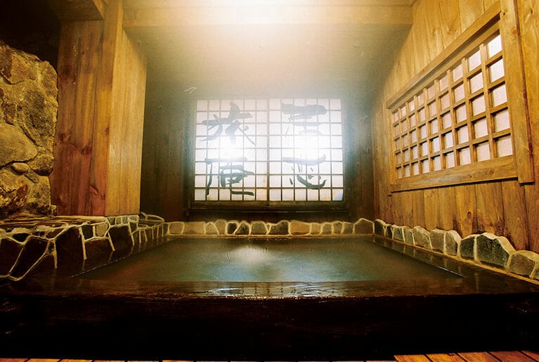 【黒川温泉 いこい旅館】本館と同じ障子がある混浴の箱湯。湯船の底に敷かれた小石が足裏を気持ちよく刺激。