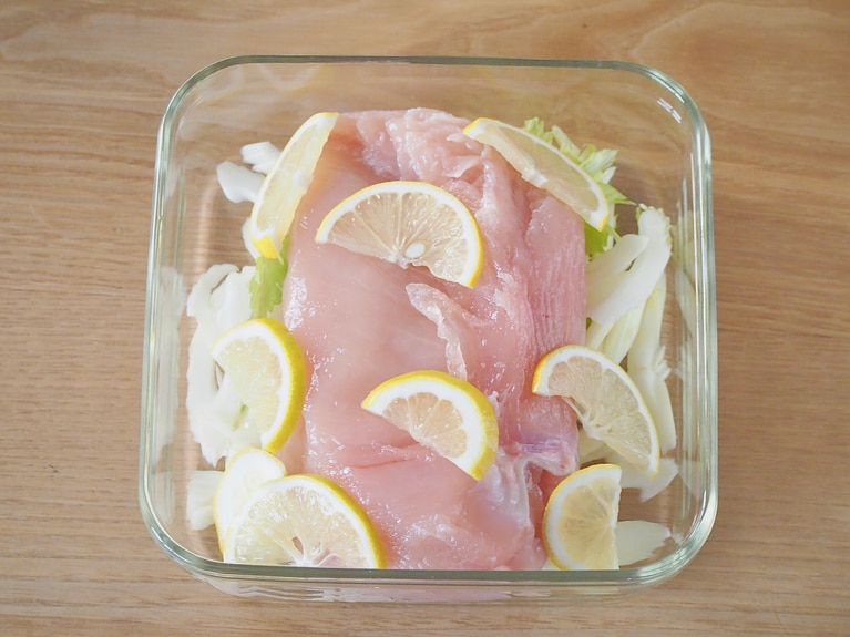 耐熱の器にセロリの軸の部分を敷き、（1）の鶏肉、レモンをのせる。レモン、セロリの葉は飾り用に少量残しておく。