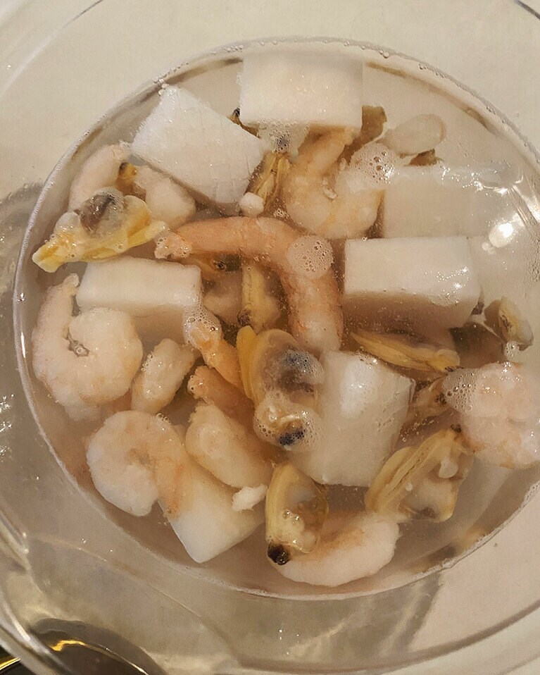 【ブイヤベースごはん】(1) 玉ねぎはみじん切り、トマトはざく切りにしておく。にんにくはおろしておく。シーフードミックスは海水と同じ濃度に調整した塩水につけて表面の氷を溶かし、キッチンペーパーで水気をふき取っておく(半解凍でOK)。