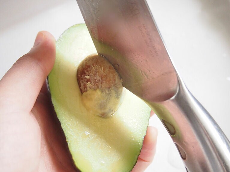 種を中心にして、アボカドを割ったら包丁で種を取り除く。
