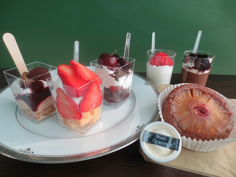 左から「カシスマロンケーキ」280円、「ショートケーキカップ」250円、「ブラックフォレストケーキカップ」250円、「のーこー」250円、「チョコレートパンナコッタ」250円。手前「アップサイドダウンケーキ」300円。
