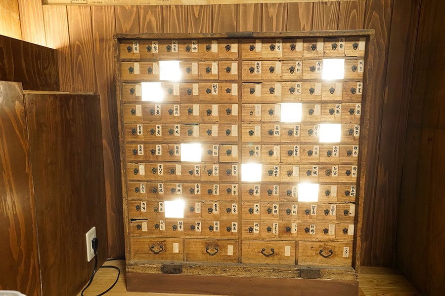 薬の名前がかかれた小さな引き出しがたくさんある薬箱は、照明が仕込まれてインテリアの一部になっている。