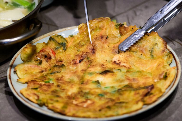 カリッと香ばしく焼き上げた、具沢山の海鮮チヂミ（20,000ウォン）も必食。ソジュ（韓国焼酎）が進みます。