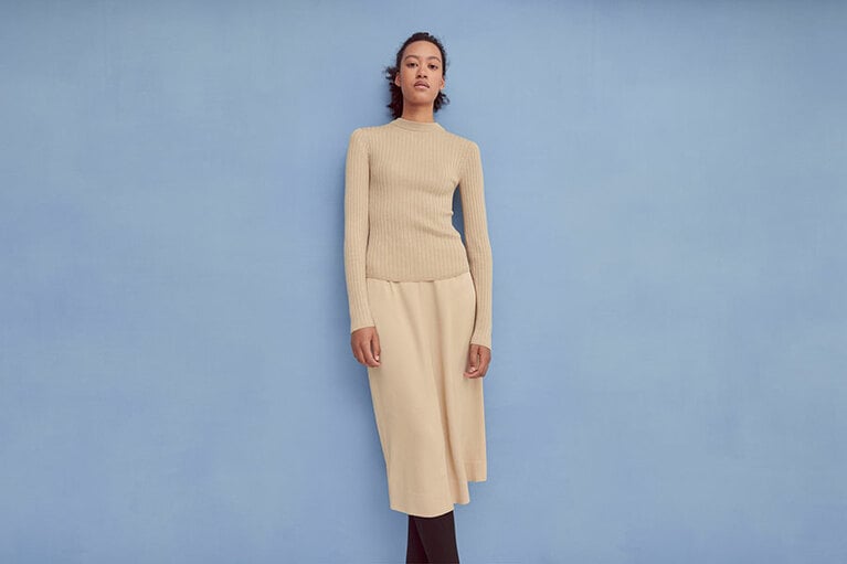 エクストラファインメリノリブクルーネックセーター(長袖) 2,990円、サテンミディスカート 3,990円。