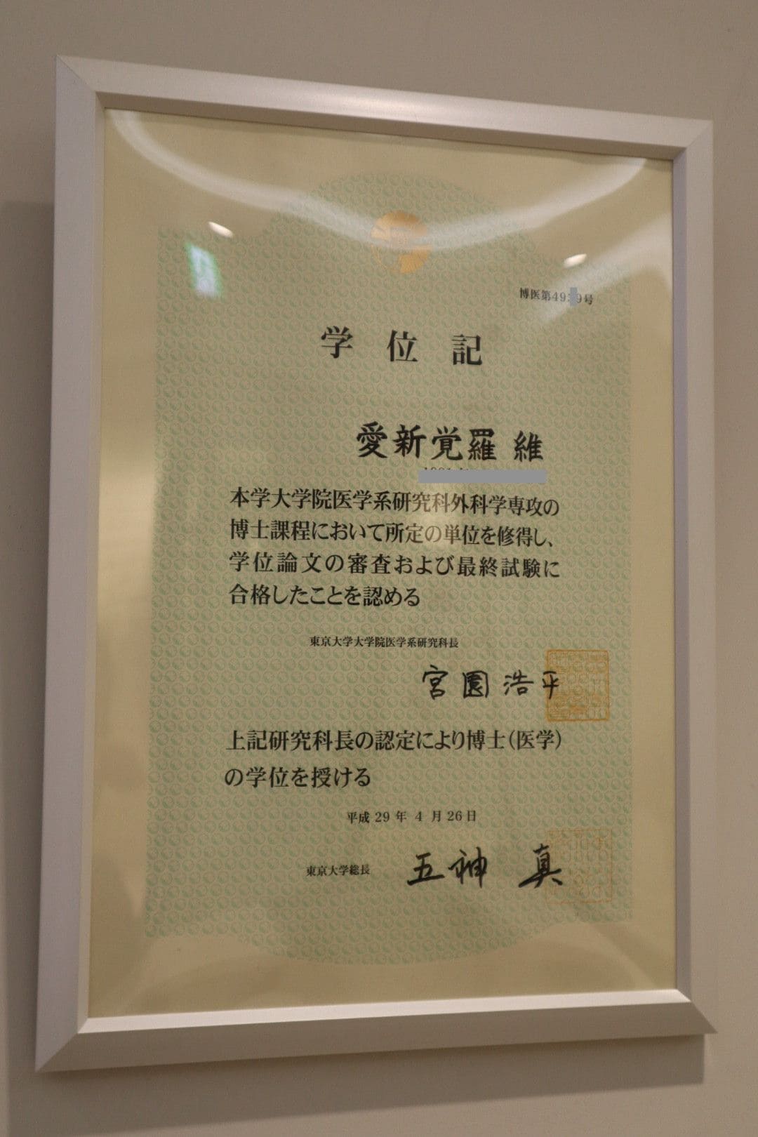 病院内に掲げられている東大医学博士の学位記。医師免許と博士号はいずれも愛新覚羅姓で取得。中国国内を含む海外での学会発表や論文執筆も「Wei Aixinjueluo」名義だ。（著者撮影）
