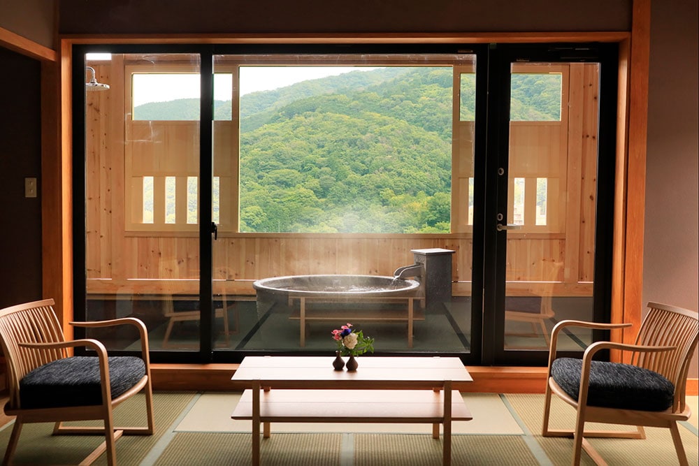 宿は高台に位置し、客室から四季折々の景色が望める。写真は80平米の広さを持つ、温泉半露天風呂付きデラックスルーム。
