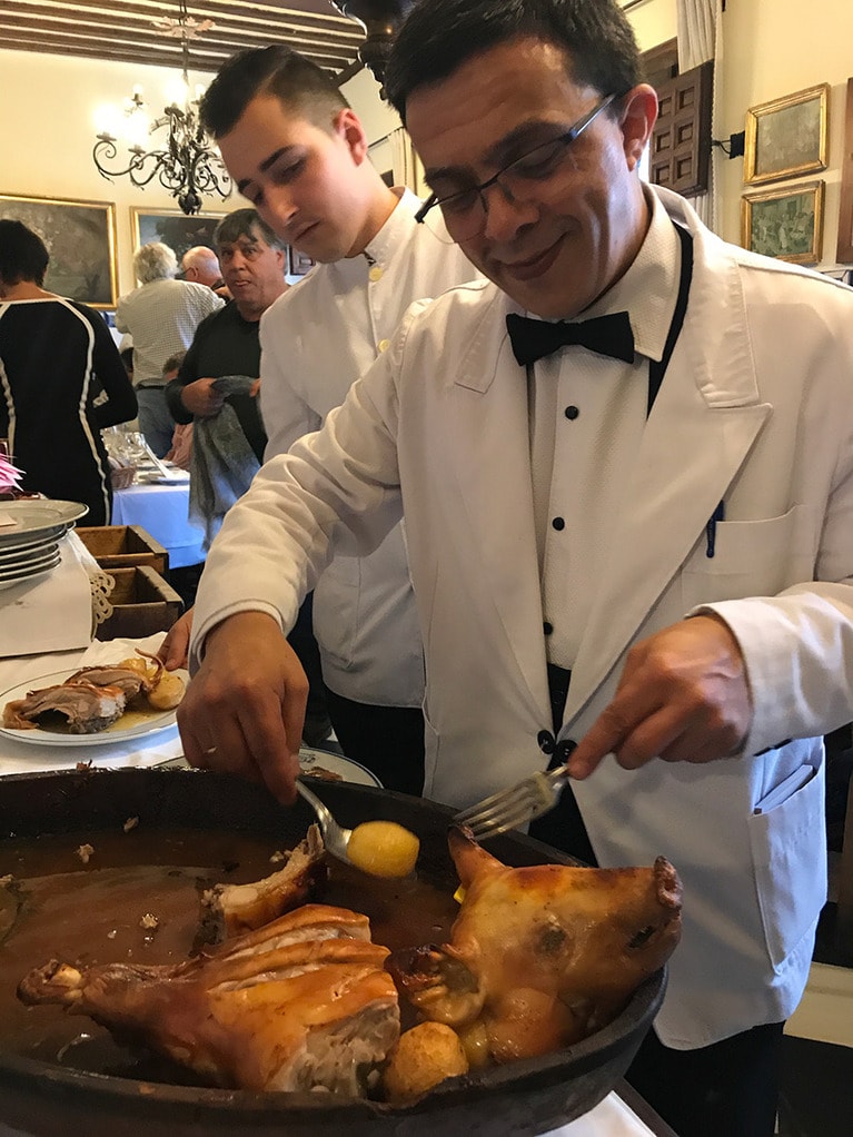 乳飲み豚の丸焼きを切り分けるベテランウェイター。その横には手元を見つめる若手ウェイターの姿が。こうして伝統が受け継がれていく。