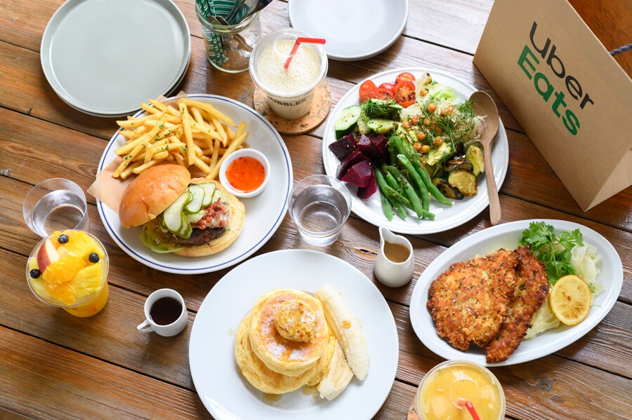 この日のランチは、片桐さんの大好きなレストラン「bills」と「ジューススタンド バブルス」。右上 Uber Eats の紙袋から時計回りにチョップドサラダ、パルメザンチキンシュニッツェル、リコッタパンケーキ、和牛ハンバーガー。