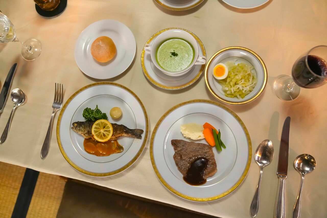 当時の松江で手に入る食材で山橋（柄本時生）が作ってケータリングした洋食のフルコース。ニジマスの詰め焼き・バターソース添え、和牛のステーキ・グレービーソース、キャベツとゆで玉子の酢漬け、えんどう豆のポタージュスープには司之介が職場から調達してきた牛乳が使われている、という設定　（C）NHK