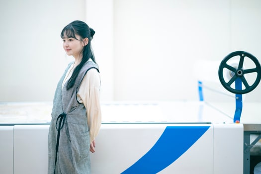 ゆったりとしたフォルムのオーバーオールとブラウスを合わせて着用した山田さん。私服でも着心地のよい大きなシルエットのパンツを好んで穿いているそう。リネン天然染めギャザーブラウス（OFF WHITE）30,800円、［UpcycleLino］ギンガムアシメサロペット（CHECK）37,400円／ネストローブ