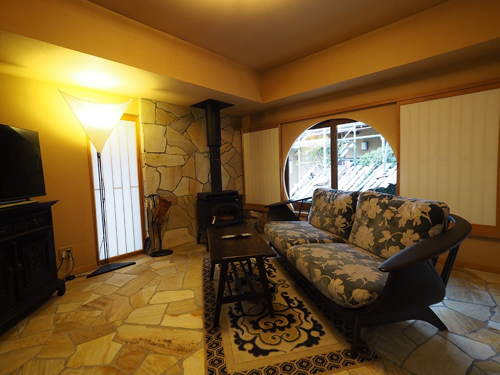 飛騨家具のソファや暖炉が備わった、柔らかな光を届ける和紙のシェードランプが照らす洋室。