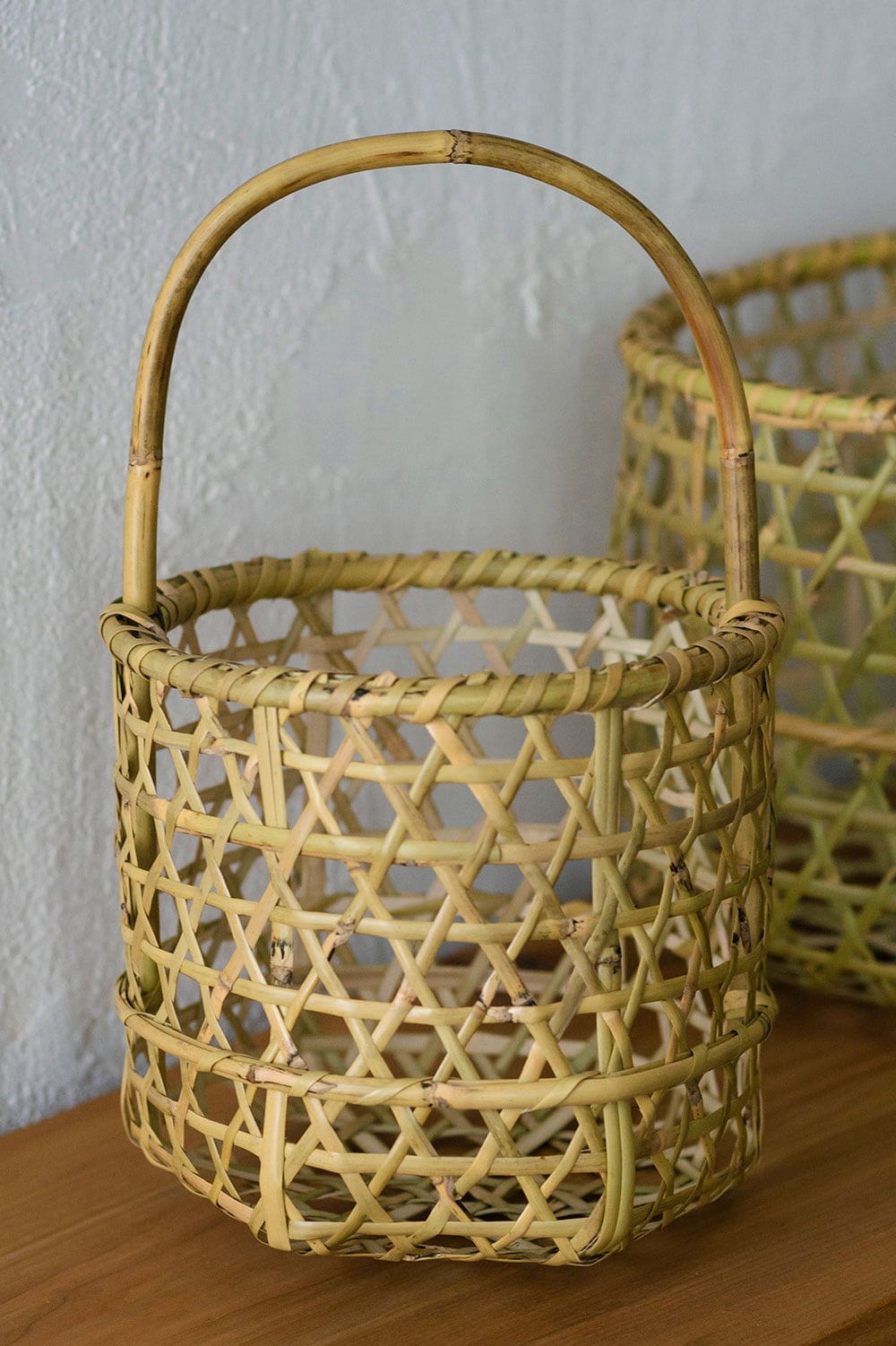 ハンドバッグにもちょうどよさそうな円筒形の根曲がり竹の手提げ籠。